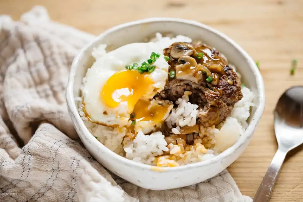 loco moco served in a rice bowl donburi digged in with a spoon