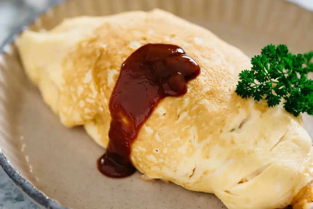 yoshoku omurice served on a plate ketchup drizzling on omrice