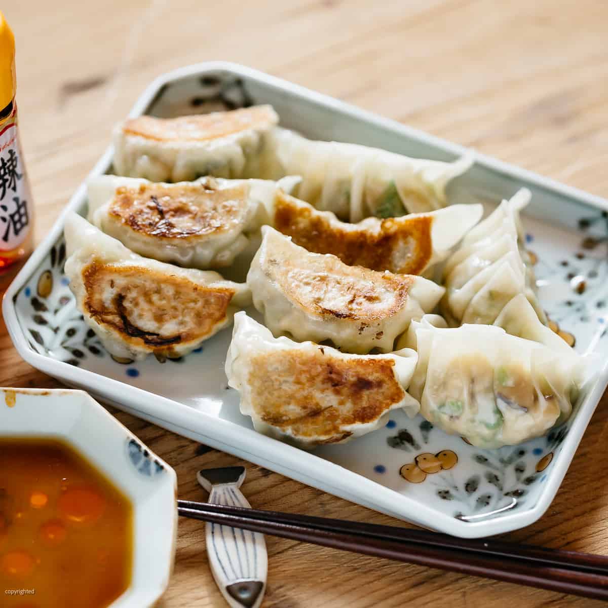 9 vegetable gyoza served on a rectangle plate with a pair of chopsticks