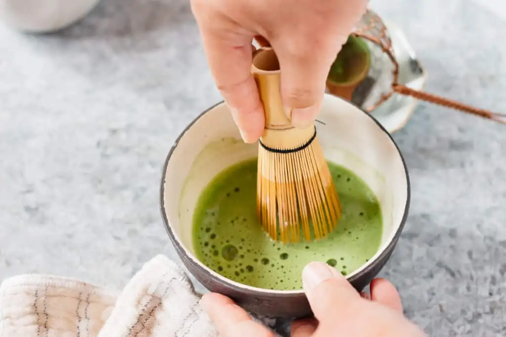 making matcha with a bamboo whisk in a tea bowl
