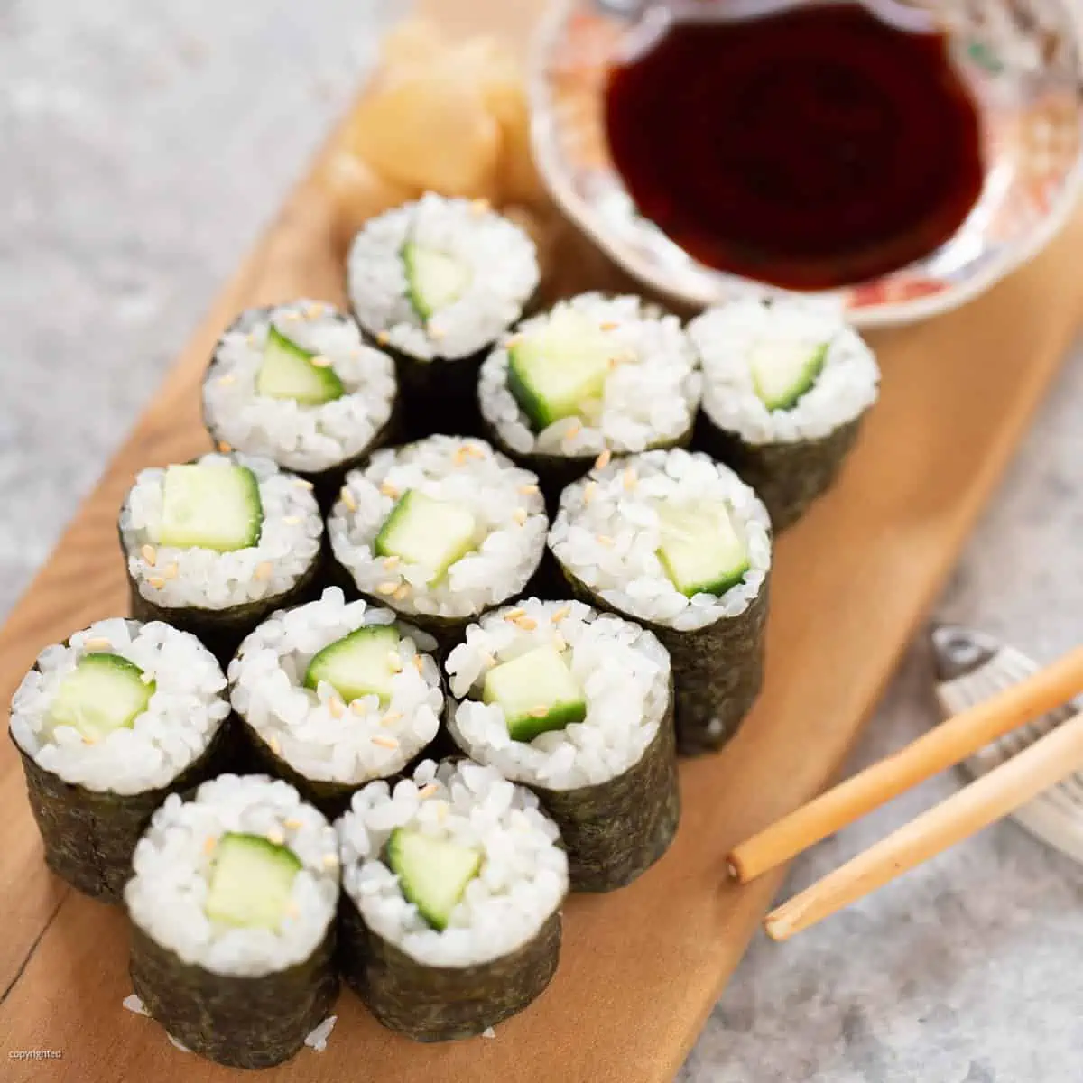 kappa maki cucumber rolls are served on a wooden plate with a small bowl of soy sauce