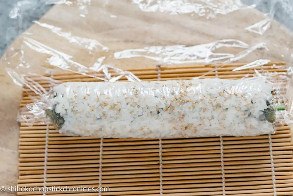 uramaki sushi roll on a bamboo sushi rolling mat and cling wrap