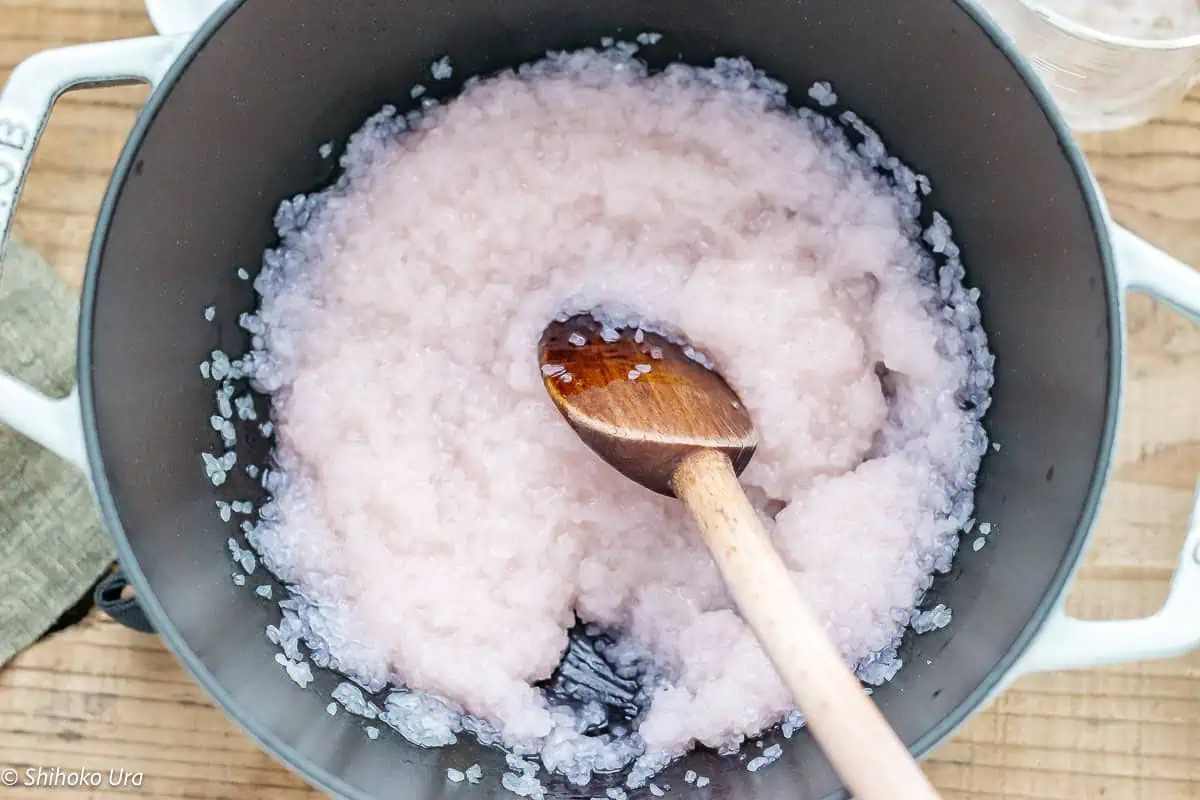 Cooking pink coloured water, sugar and domyojiko over low to medium heat and stir constantly with a wooden spatula