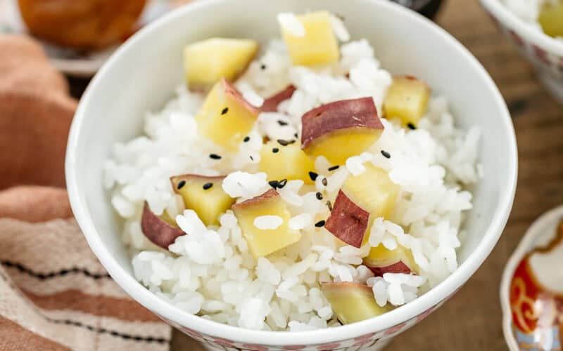 sweet potato rice served in a small rice bowl with umeboshi, and pickled daikon in a small dish in background