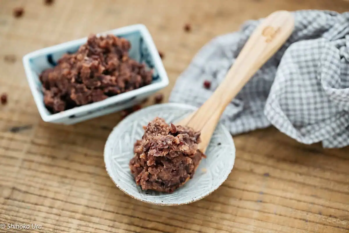 fermented naturally sweet red bean paste on a wooden spoon and in a rectangle dish.