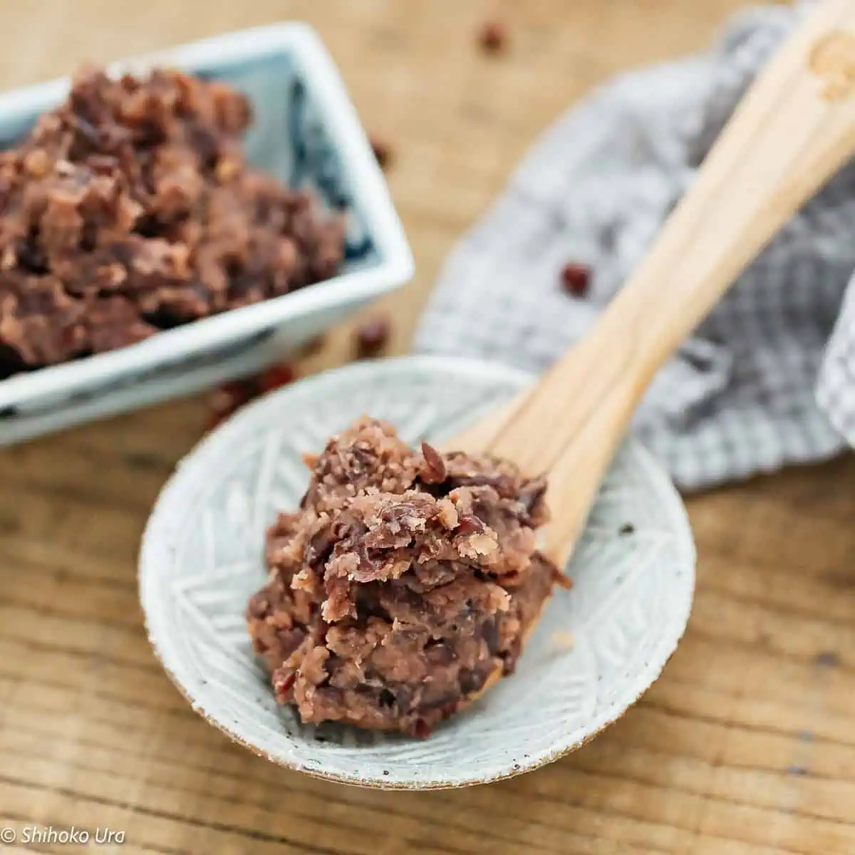 naturally sweet fermented red bean paste on a wooden spoon and red bean paste in a square bowl in background