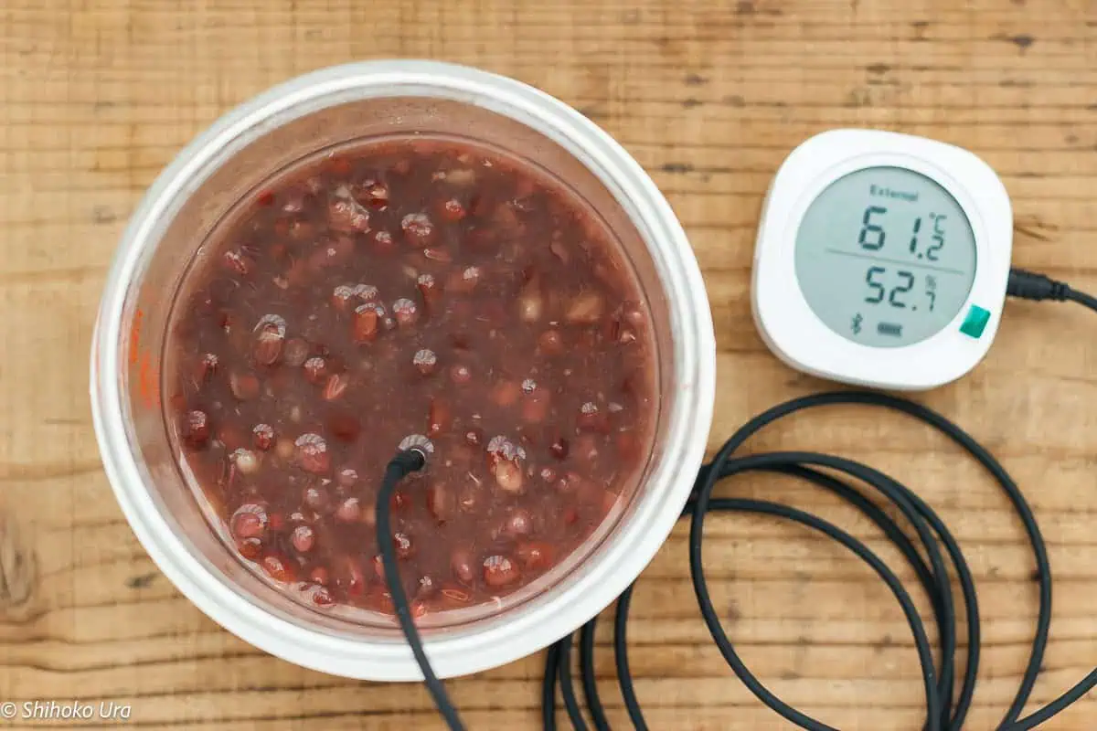 cooked azukibean in a glass yoghurt maker container with thomoeter sticked into the container