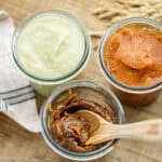 three different koji seasonings in glass jar with a wooden spoon