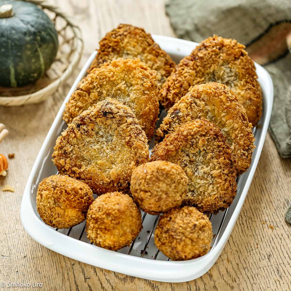 Crispy kabocha korokke served on a white dish with a rustic background.